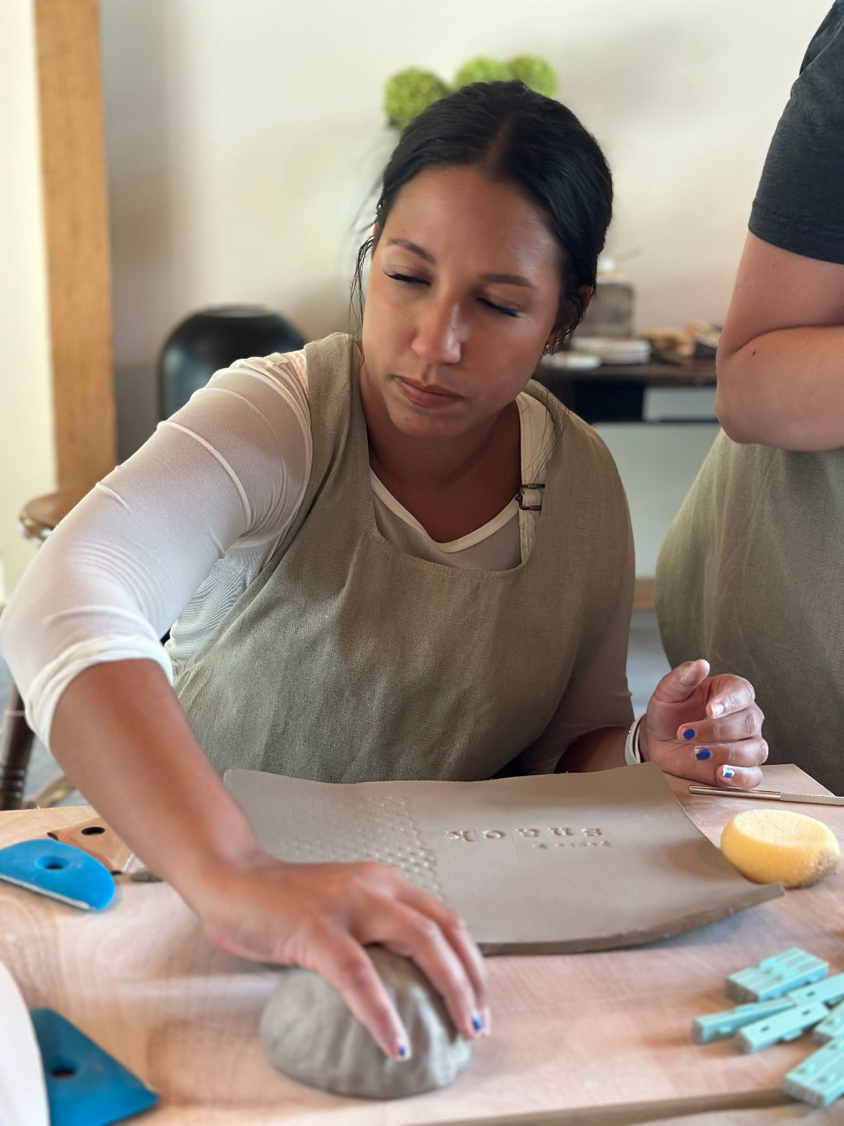 Person working with clay on a pottery wheel in a studio setting