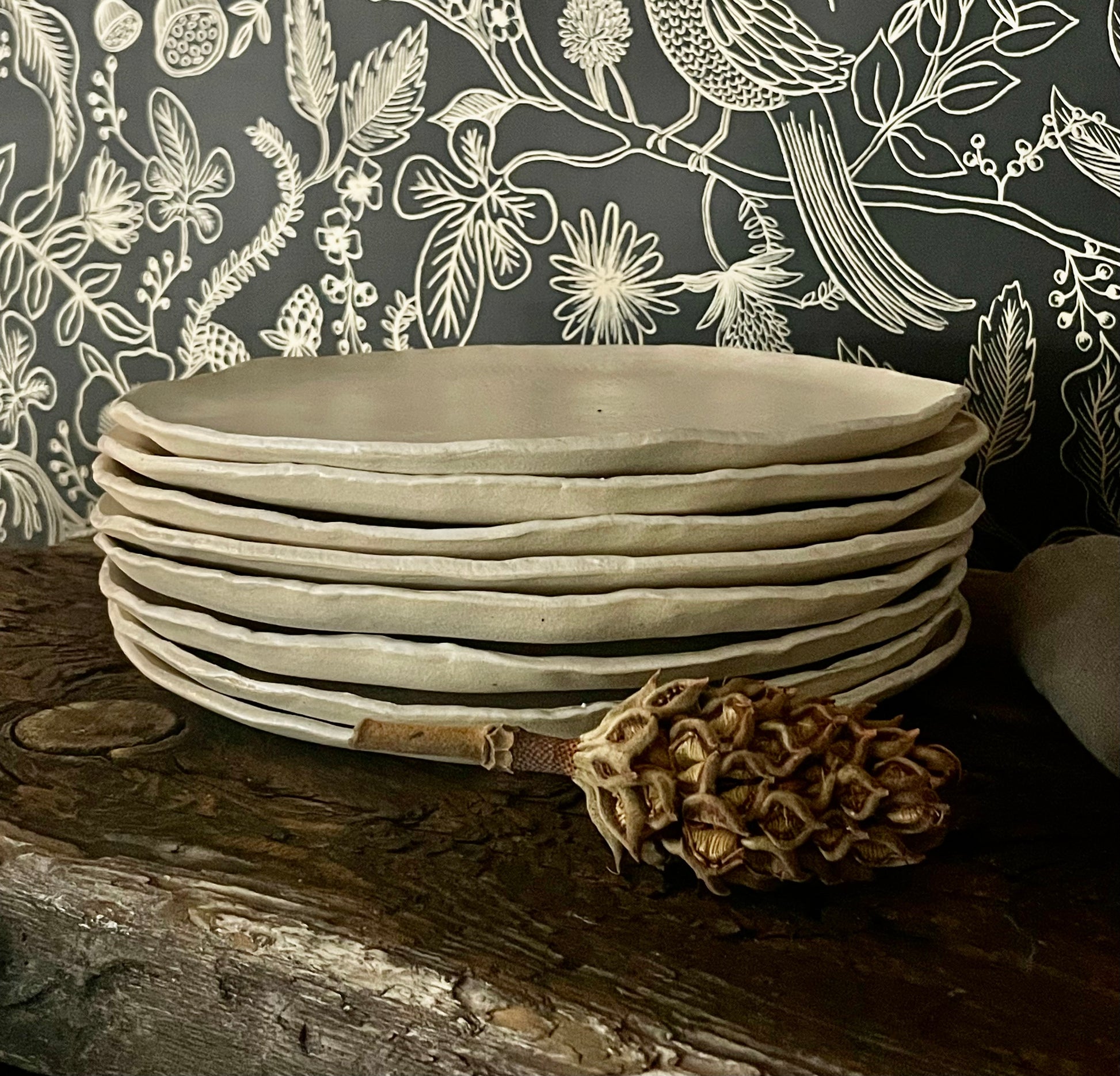 Stack of handmade pottery dinner plates in matte white with rough edge.
