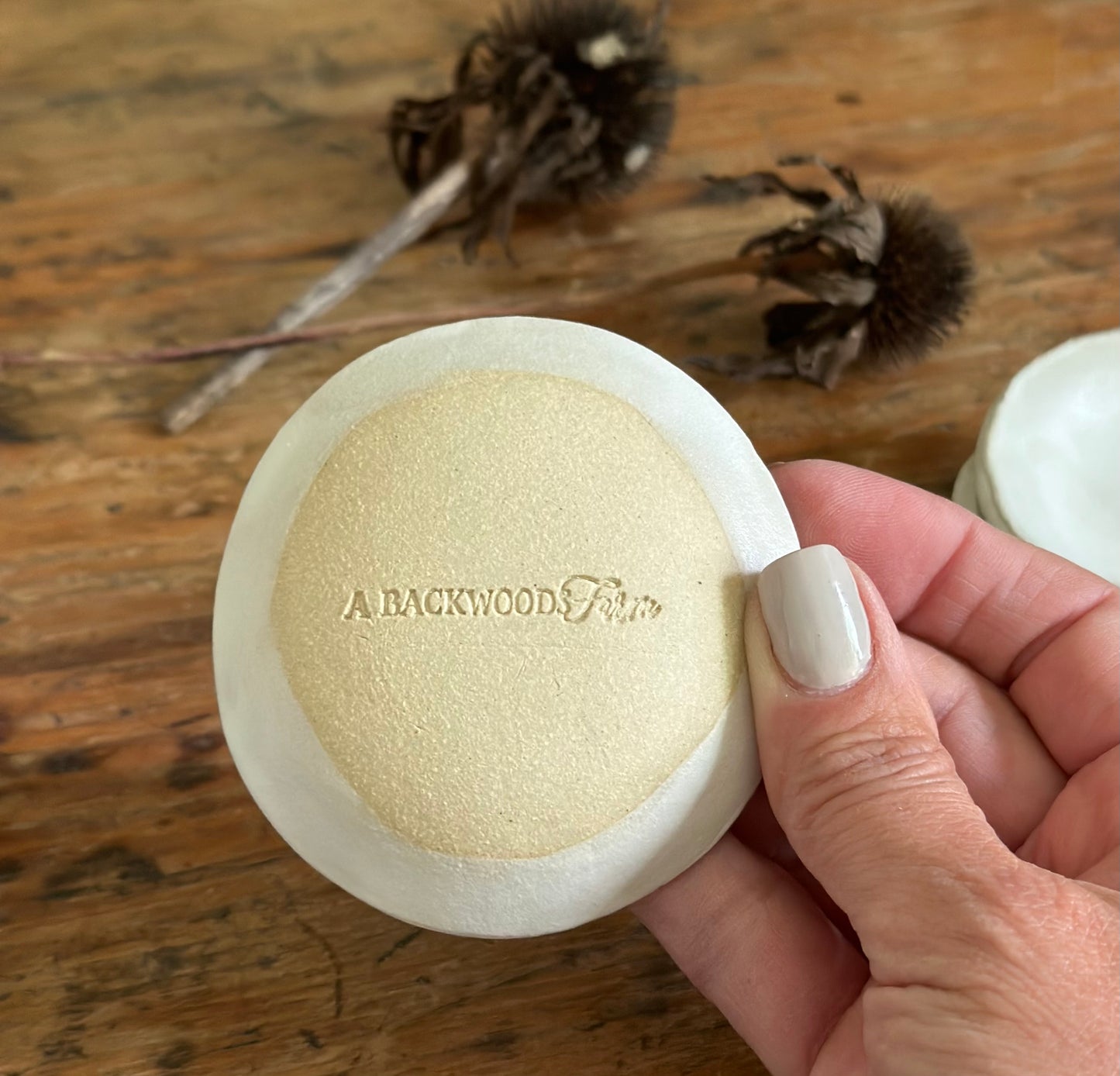 Back side of handmade tiny matte white bwol with makers mark stamp A Backwoods Farm.